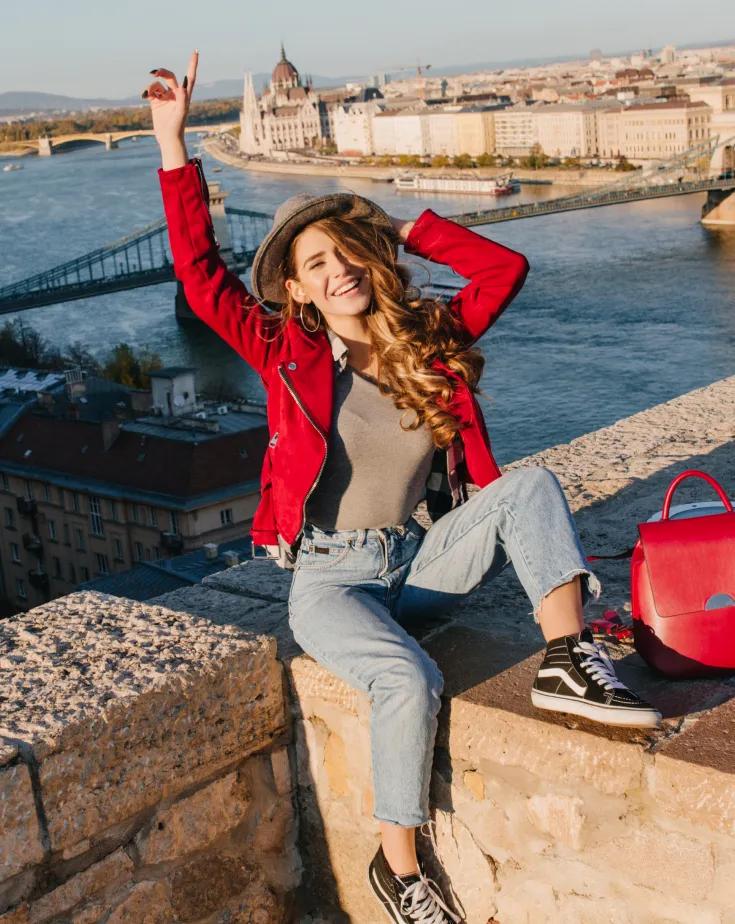 A young lady on a red jacket posing from a rooftop